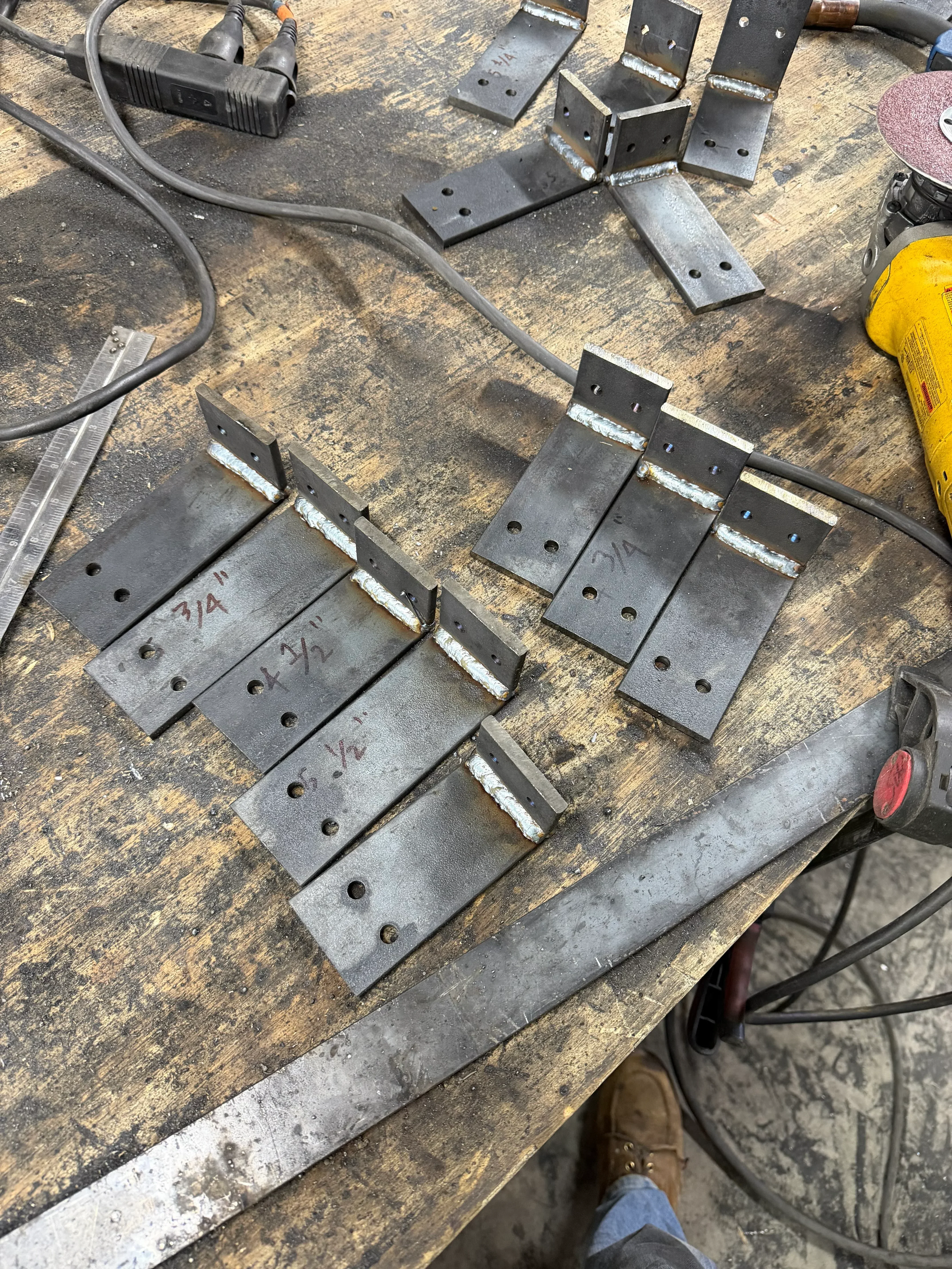 Steel hinges with drilled holes and welded reinforcement plates on work surface