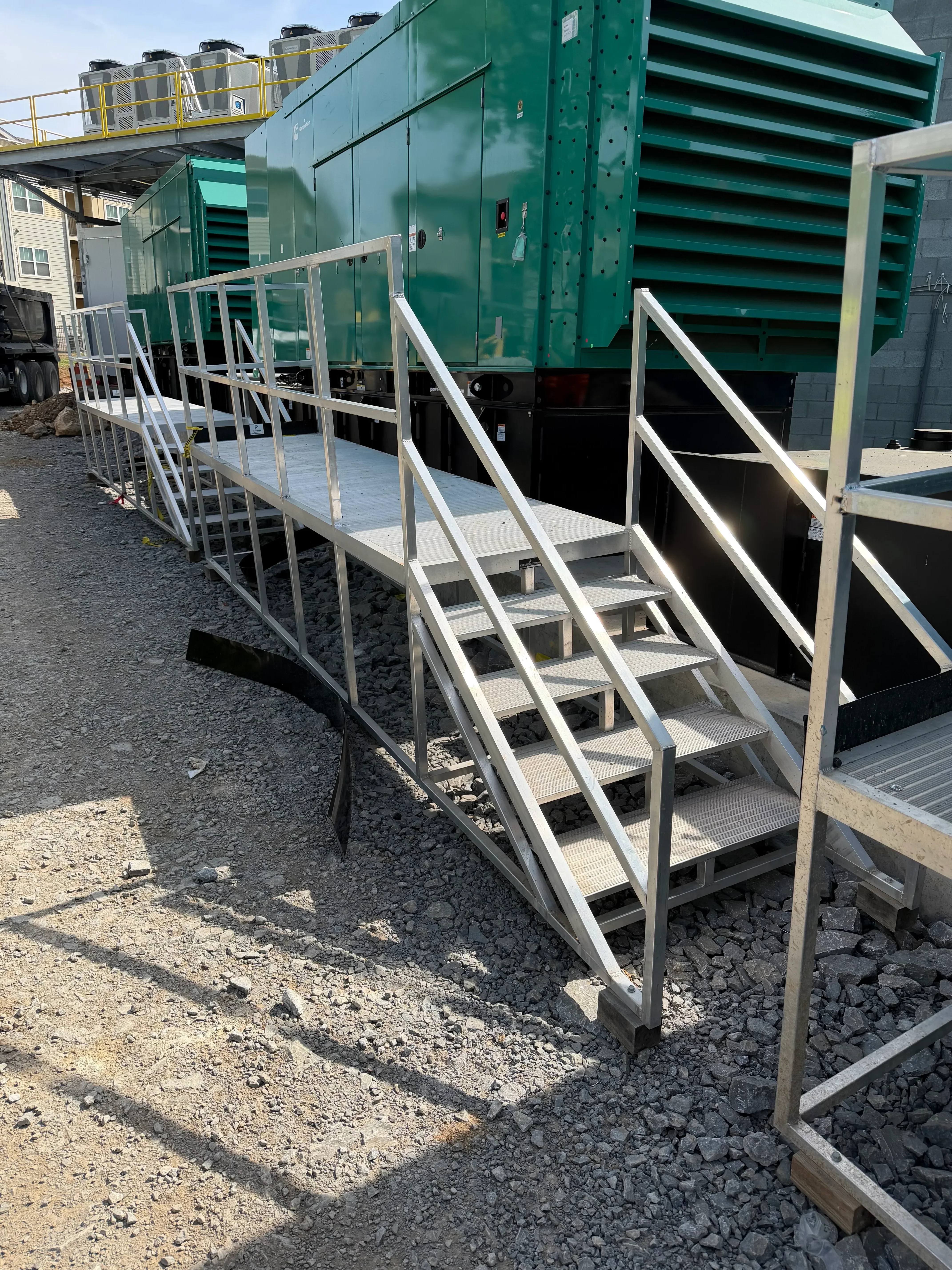 Welded steel staircase with angled stringers, metal handrails, and multiple landings on industrial site