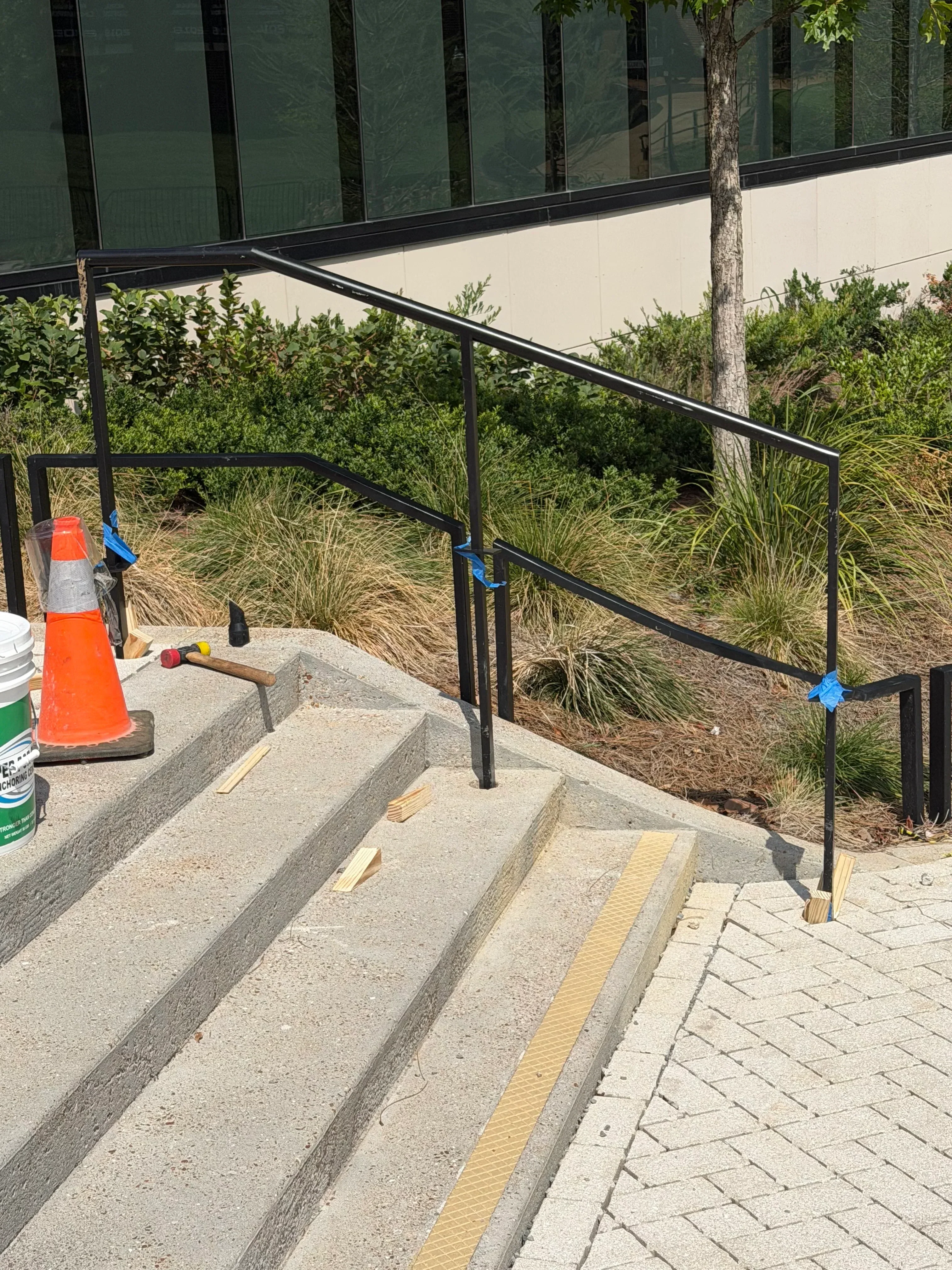 Black steel stair railing with welded square tubing on concrete steps