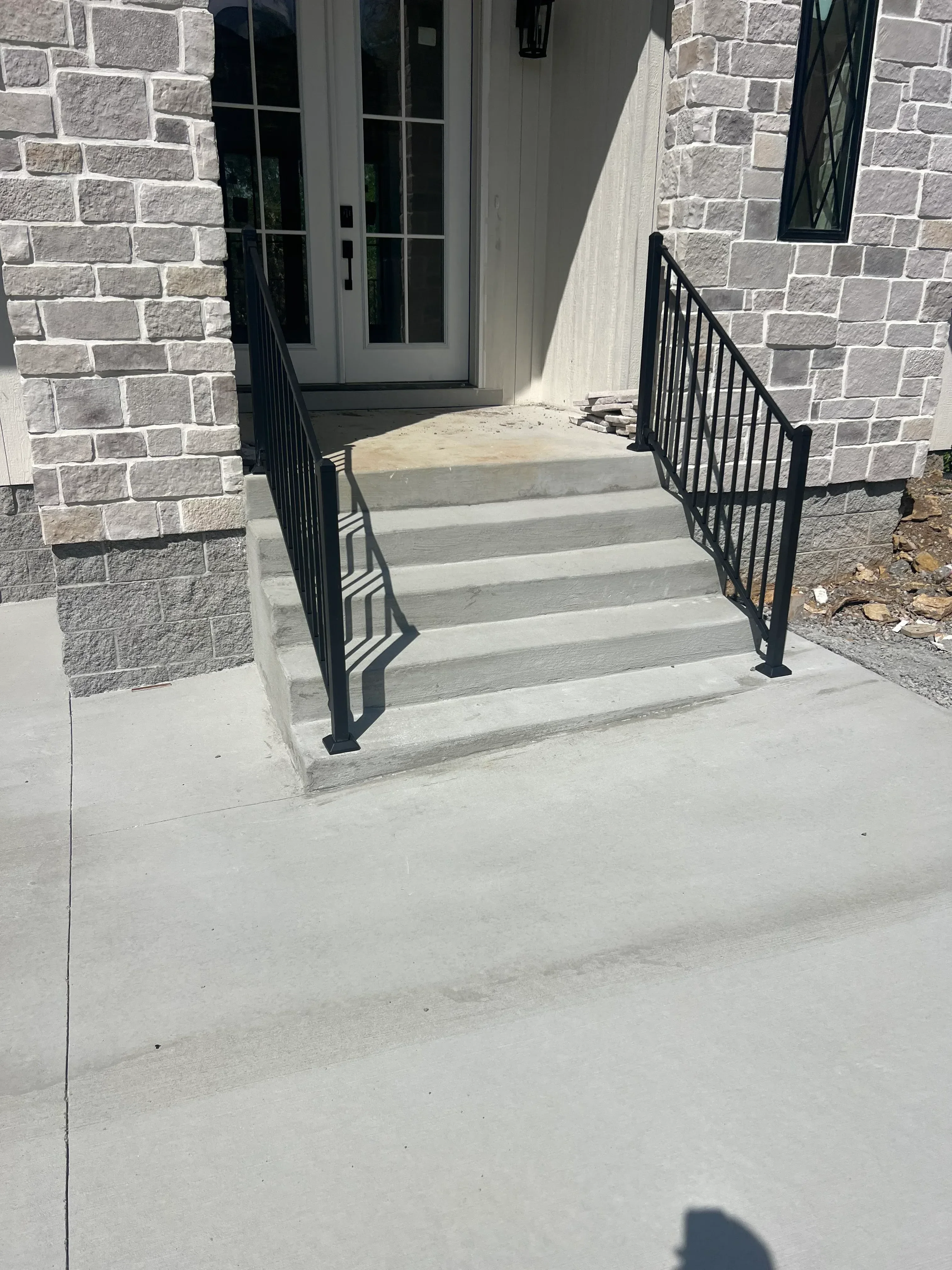 Black metal wall shelves with slat design mounted on exterior stone and stucco wall