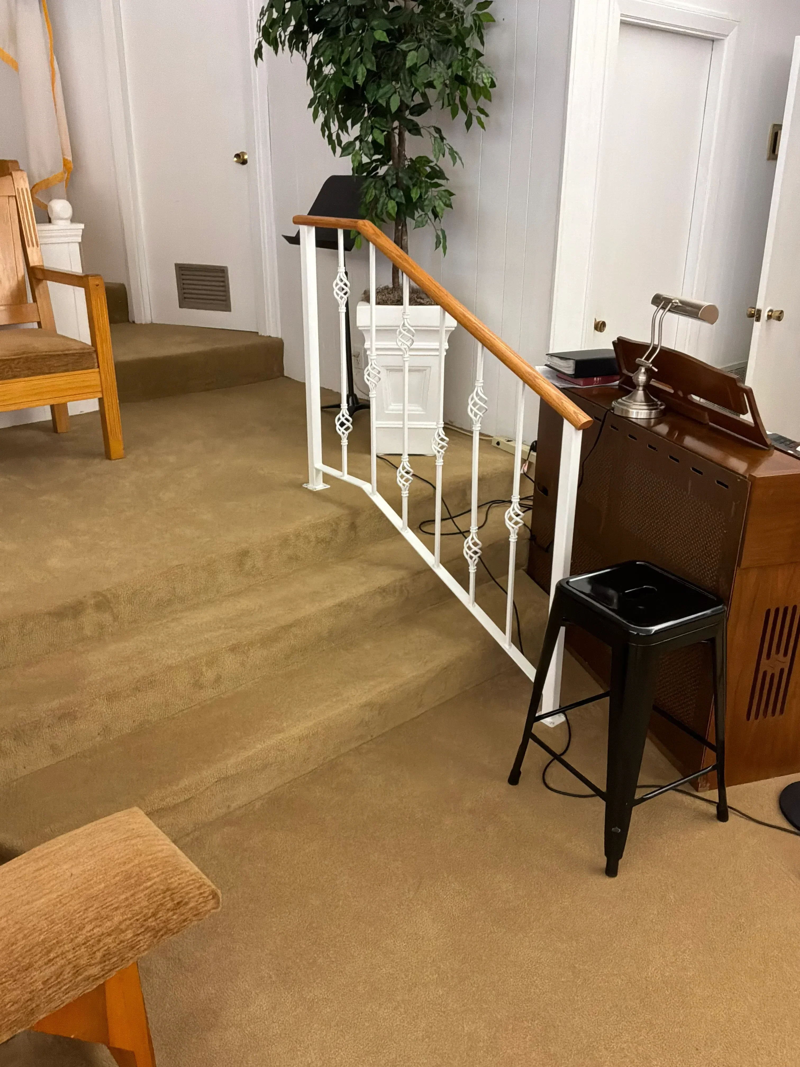 White metal stair railing with decorative balusters and wood handrail in residential interior
