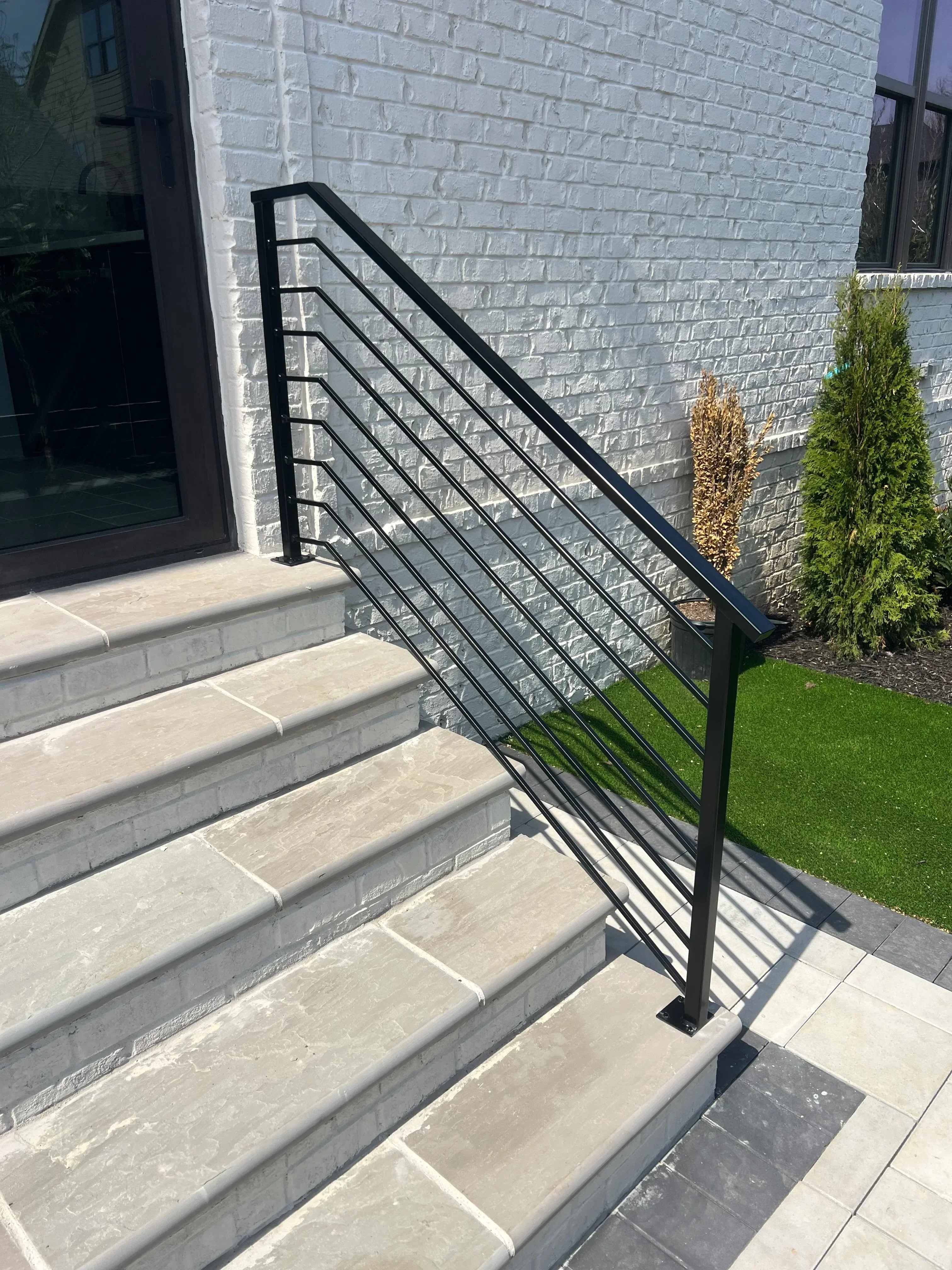 Black steel stair railing with horizontal pickets on concrete steps