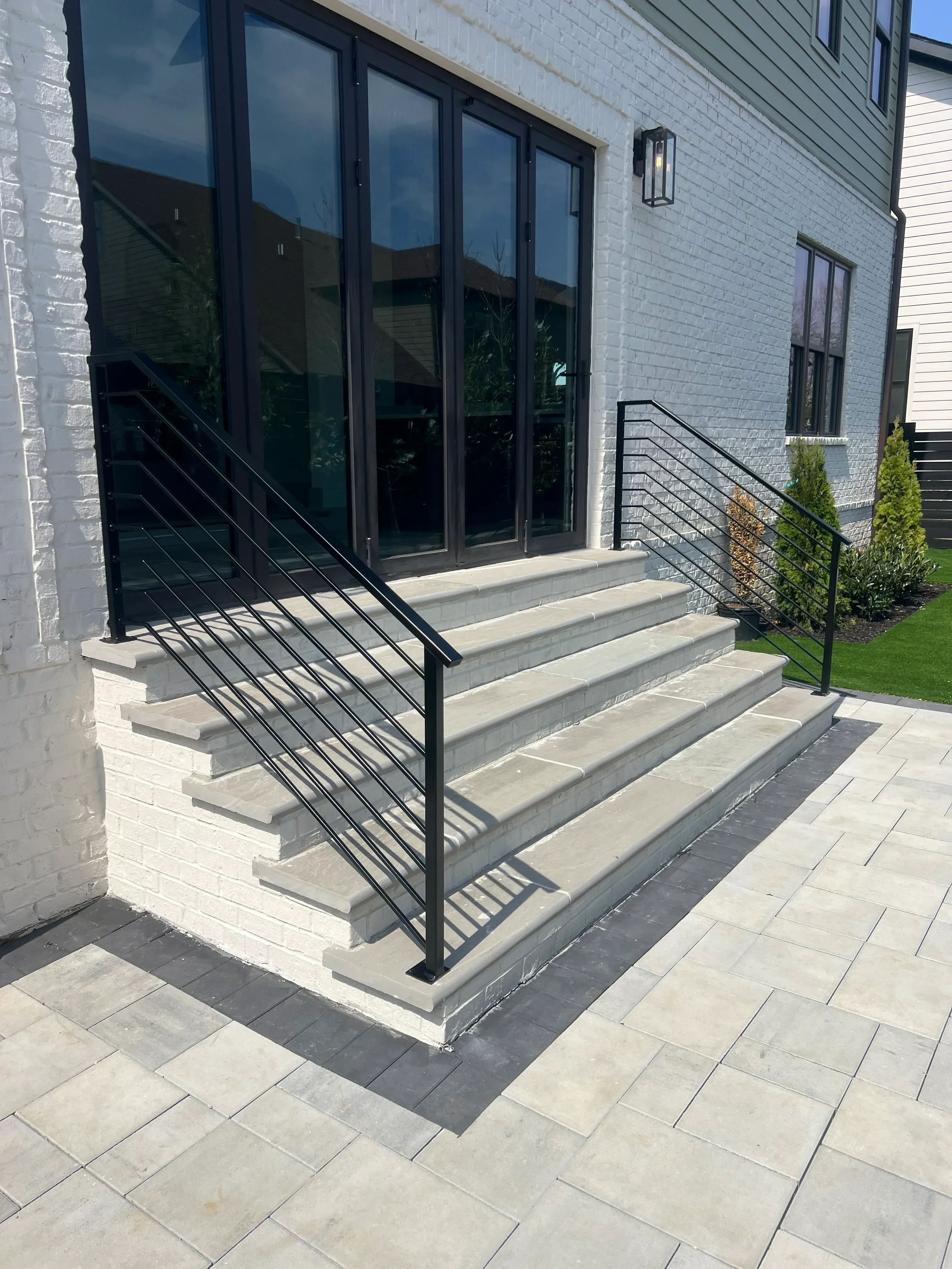 Black metal stair railings with horizontal pickets on concrete exterior stairs