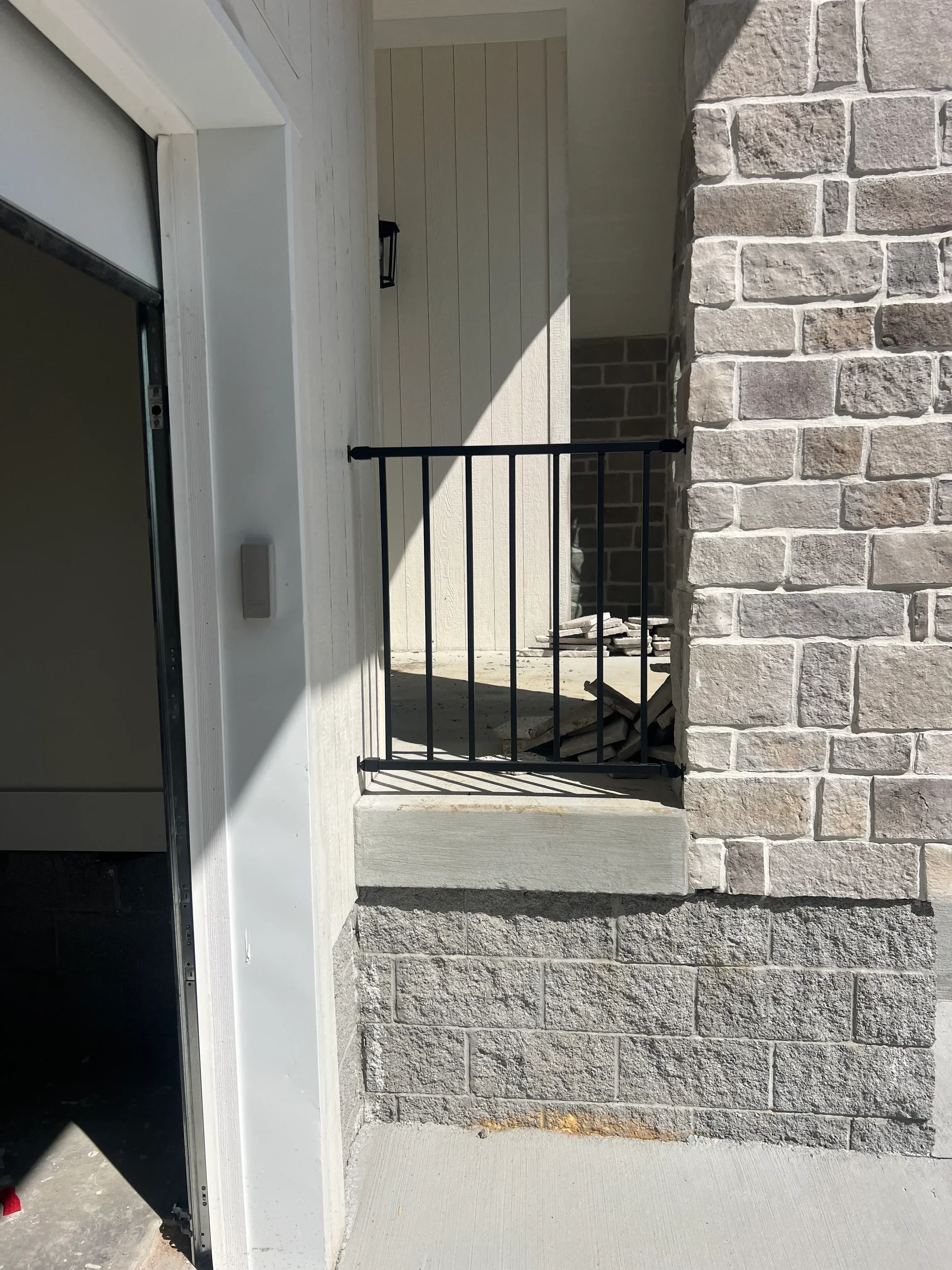 Black metal gate and horizontal bar railing at stone-clad residential entrance