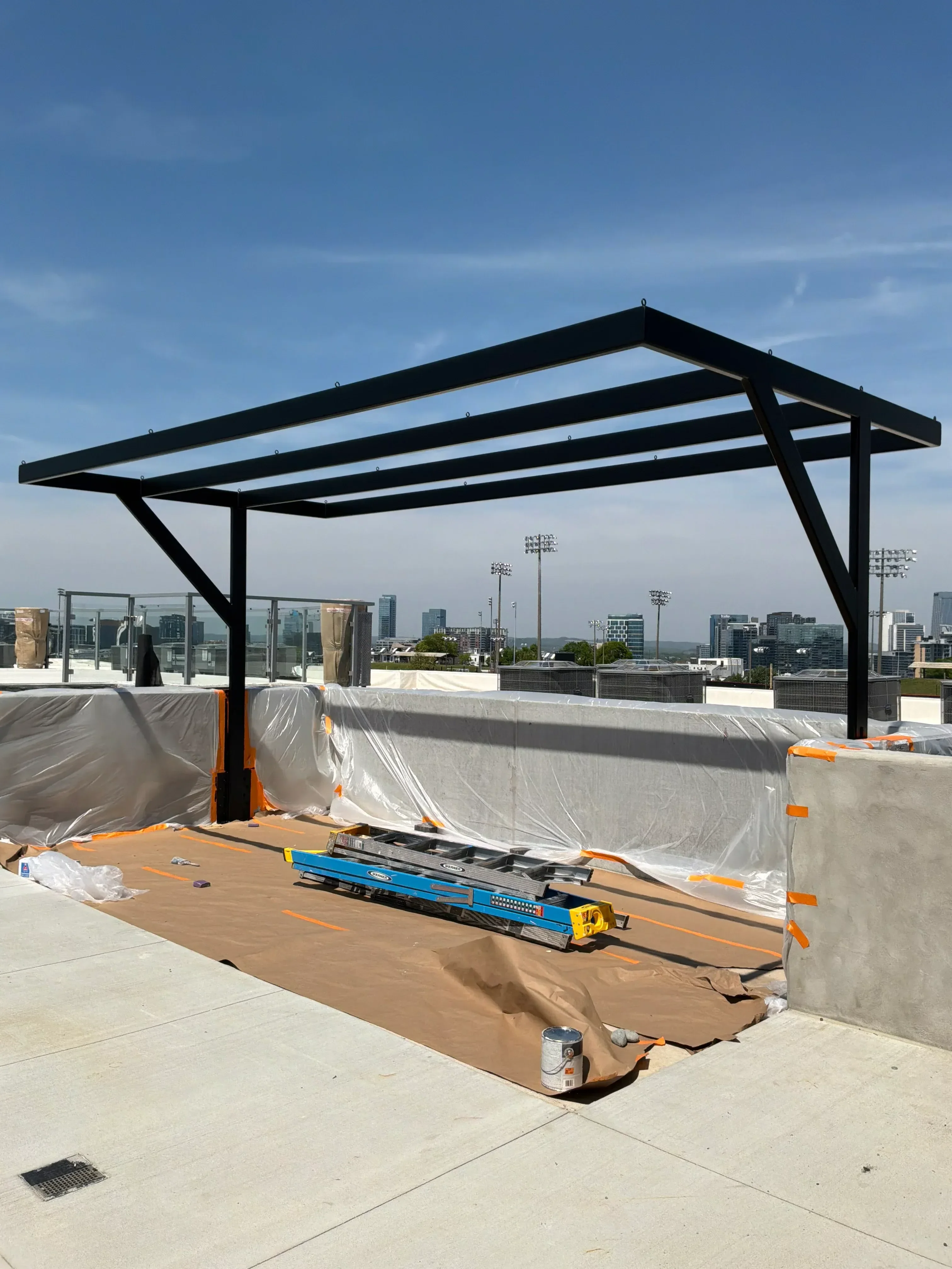Black steel structural frame with diagonal bracing on rooftop concrete deck
