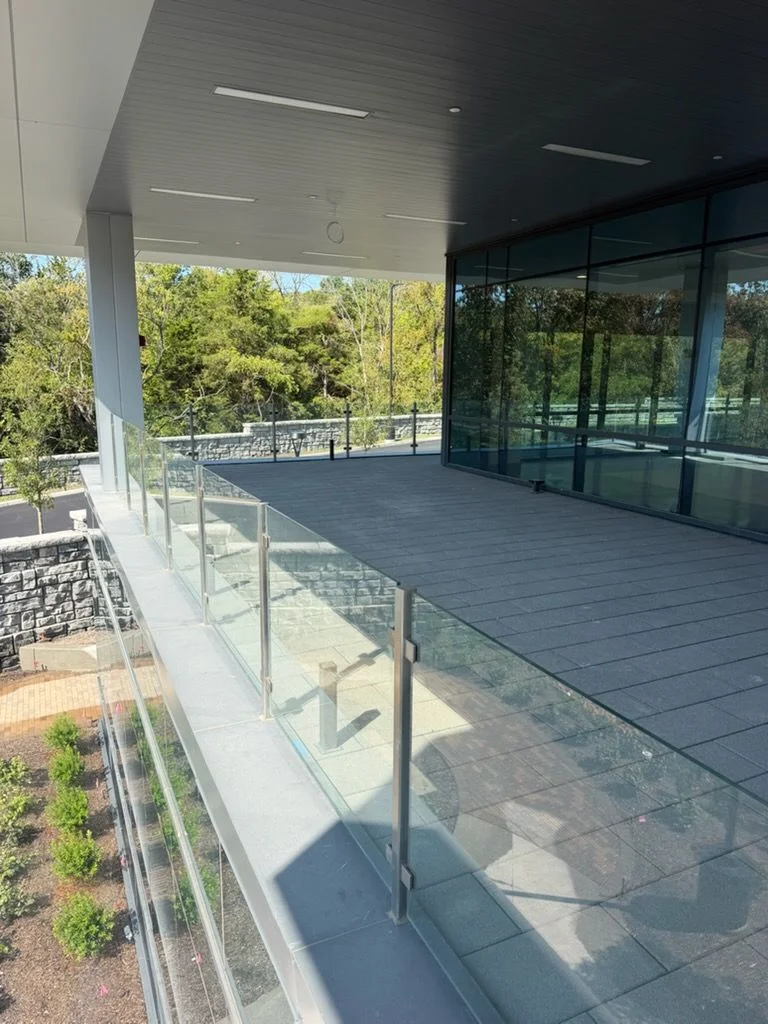 Custom glass railing panels installed along an interior staircase in a Nashville-area home, showing clear tempered glass panels with metal hardware against an open-concept living space.