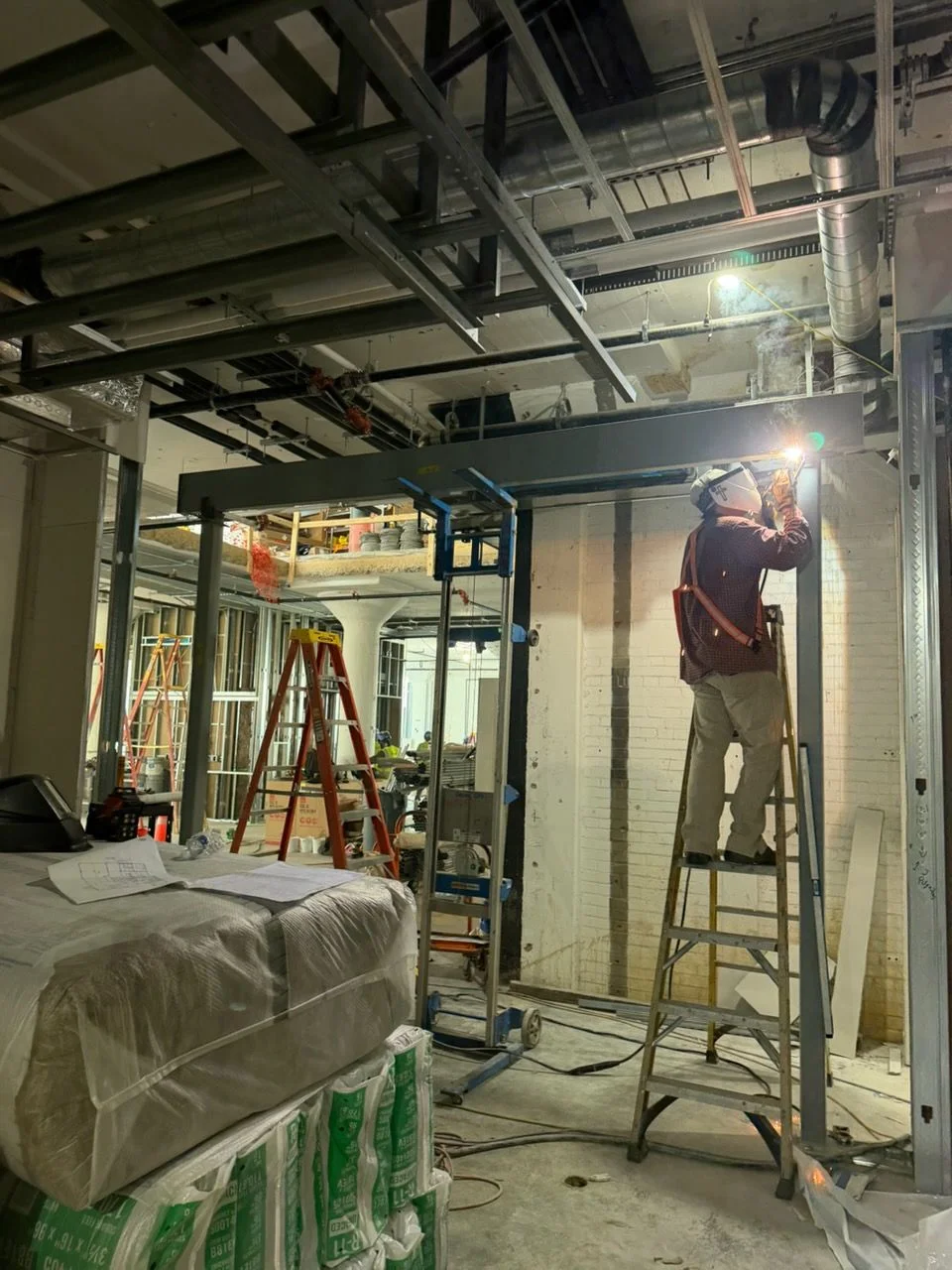 Custom structural steel beams and columns fabricated by Accurate Fabrication, staged for installation on a residential construction site in the Nashville, Tennessee area. Welded connection plates and brackets are visible on each structural component.